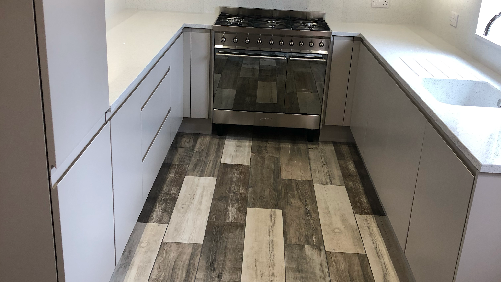 Grey fitted kitchen cabinets around a range cooker