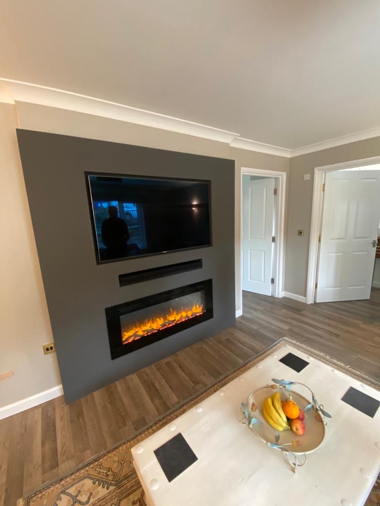 A bespoke charcoal media wall with inset television and recessed electric fire